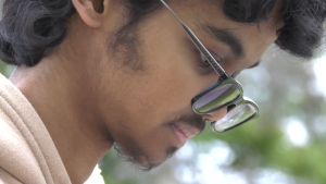Saad Asad, a College of the Canyons Student wearing dark rim glasses looking down at a book off screen.